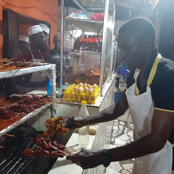 man preparing mishikaki beef skewers at a street food stall in dar es salaam