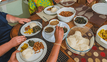 table with serving dishes and plates of zambian food with hand reaching