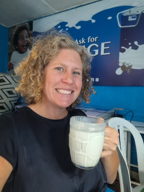 woman in blue shirt holding a glass of milk