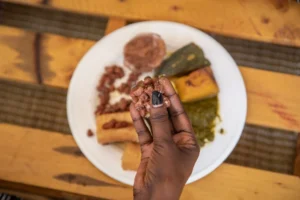 hand holding cooked beans over a plate of rwandan food