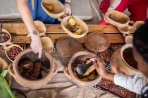 hands serving food out of traditional rwandan pots