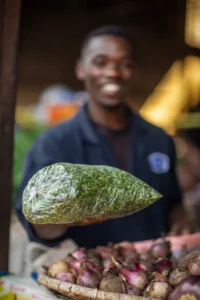 man passing bag of chopped green cassava leaves