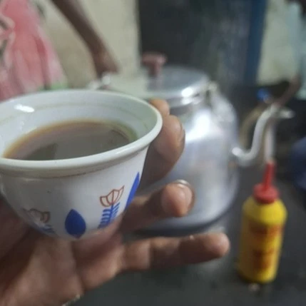 hand holds a small cup of coffee